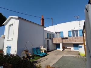 a white house with a patio and two chairs at MER 12 à 14 pers L'Aiguillon sur mer in LʼAiguillon-sur-Mer +43 photos