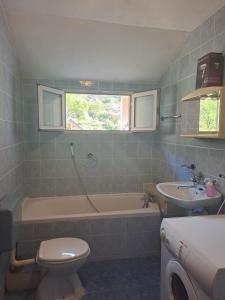 een badkamer met een bad, een toilet en een wastafel bij Bradley apartmants HR in Račišće