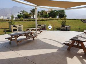two picnic tables under an umbrella on a patio at Jebel Sifah Suites in As Sīfah