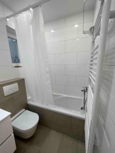 a white bathroom with a toilet and a bath tub at Apartments Stone in Vrsi