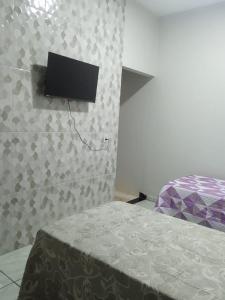 1 dormitorio con 1 cama y TV en la pared en Hotel Enlace, en Ji-Paraná