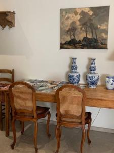 una mesa de comedor con 2 sillas y jarrones. en La Zoulette, en Louveigné