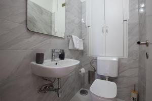 een badkamer met een wastafel, een toilet en een spiegel bij MS 3BR Apartment near Kolovare beach in Zadar +39 foto's