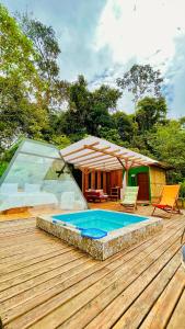 a wooden deck with a swimming pool and a house at Macas Glamping in Macas