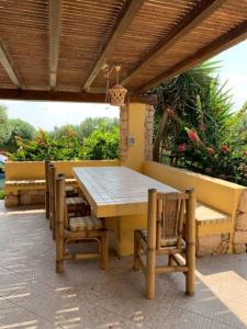 Villa Maveda, un dammuso immerso nel verde في لامبيدوسا: طاولة وكراسي خشبية تحت سقف خشبي