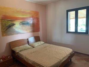 1 dormitorio con 1 cama con una pintura en la pared en Villa Maveda, un dammuso immerso nel verde en Lampedusa