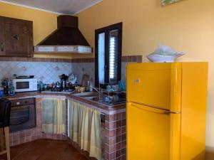 a kitchen with a yellow refrigerator and a sink at Villa Maveda, un dammuso immerso nel verde in Lampedusa
