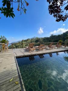 a swimming pool with benches on a wooden deck at Loma Nevada Minca Hotel in Minca