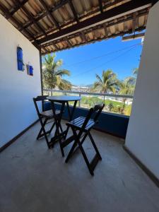 stół i krzesła na balkonie z palmami w obiekcie Hospedagem Pé Na Areia w mieście Arraial do Cabo