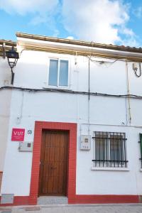 ein weißes Gebäude mit einer roten Tür und Fenstern in der Unterkunft Cuencaloft Mari De Reyes in Cuenca