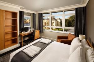 a bedroom with a bed and a desk and windows at Downing College in Cambridge