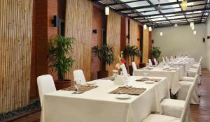 a long room with white tables and white chairs at Zizz Convention Hotel in Denpasar