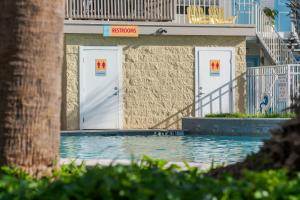 a building with white doors and a swimming pool at Gaido's Seaside Inn in Galveston