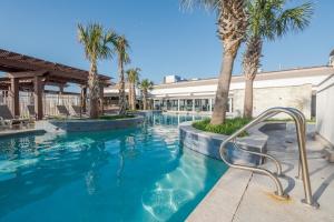 a swimming pool with palm trees in a resort at Gaido's Seaside Inn in Galveston