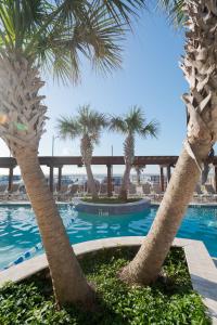 a resort with palm trees and a swimming pool at Gaido's Seaside Inn in Galveston