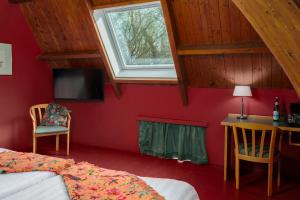 a bedroom with a bed and a desk and a window at Buitenplaats Iepenoord in Oostkapelle