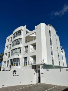 a white building with a palm tree in front of it at St Clouds Strand in Strand