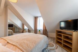 Un dormitorio con una cama y un televisor de pantalla plana. en Porto di Mare Ustka- apartament w centrum, en Ustka