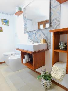 bagno con lavandino, servizi igienici e specchio di Otello Guest House a Montalcino