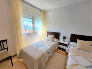 a bedroom with two beds and a window at INcostadamorte Corral da Laxe in Dumbría