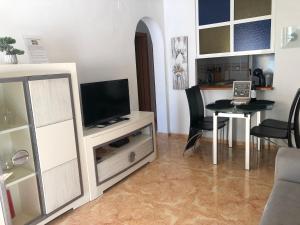 sala de estar con TV y mesa de comedor en Acogedor apartamento con piscina cerca a la playa, en Torrevieja