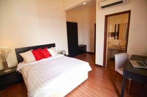 a bedroom with a bed with red pillows and a desk at Melaka Top Largest Waterpark Resort - By YouBNB Homestay Melaka in Melaka