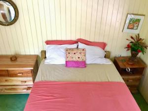 ein Bett mit einer rosa Decke und einer Tasche darauf in der Unterkunft Charlie’s Place Zion Hill - close to Blue Lagoon in Port Antonio