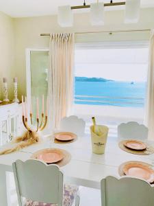 a dining room with a table with chairs and a large window at Fairy home Porto Heli in Porto Heli