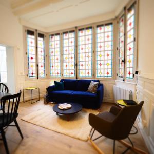 a living room with a blue couch and stained glass windows at Appartement de charme Art Déco in Vichy