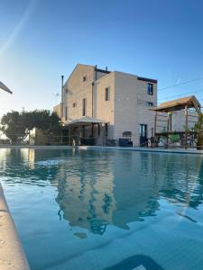 a swimming pool with blue water in front of a building at Masseria Sacramento in Palagianello