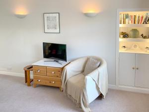 a living room with a chair and a television on a dresser at Alma Cottage in Borgue