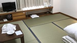 Habitación con cama, mesa y TV. en Kagetsu Ryokan en Shizuoka