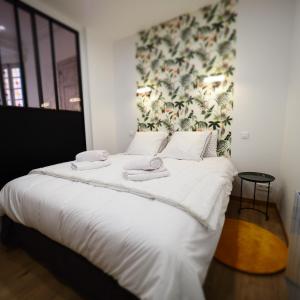 duże łóżko z białą pościelą i ręcznikami w obiekcie Appartement de charme Art Déco w mieście Vichy