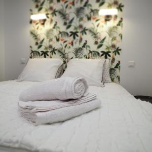 a bed with towels on it with a floral wall at Appartement de charme Art Déco in Vichy