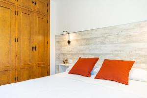 1 dormitorio con 1 cama blanca y 2 almohadas de color naranja en Apartamento Jibazahora B1, en Zahora