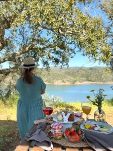 una mujer sentada en una mesa de picnic con comida y vino en Monte Do Zambujeiro, en Vila Nova de Milfontes
