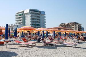un grupo de sillas y sombrillas en una playa en Eco del Mare Apartments, en Lido di Pomposa