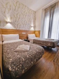 una camera d'albergo con due letti e una finestra di Hostal Comercial a Madrid