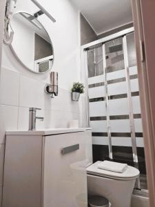 Baño blanco con aseo y espejo en Hostal Comercial en Madrid