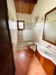 Un baño con lavabo, inodoro y espejo. en Asfodeli house, en Teulada