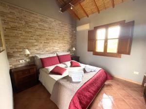 1 dormitorio con 1 cama con almohadas rojas y pared de ladrillo en Asfodeli house, en Teulada