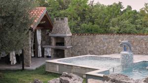 a swimming pool with a fountain and a stone wall at Villa Neval in Gostinjac