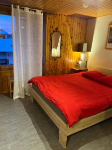 a bedroom with a red bed and a window at Au village d'Evolène, très joli studio calme et ensoleillé in Evolène