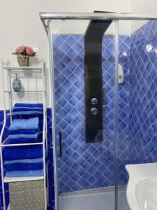 y baño con ducha de azulejos azules y toallas azules. en Riva Destra Suite apartament, en Isquia