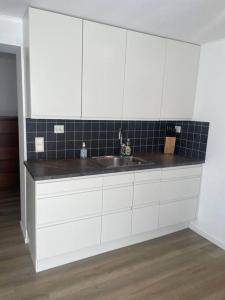 una cocina con armarios blancos y fregadero en 3 rooms apartment in Center, en Ålesund
