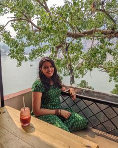 een vrouw die aan een tafel zit met een drankje bij Capt. Mount Stays in Rishīkesh +10 foto's