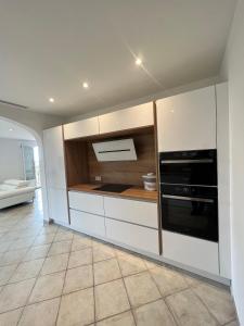 La cuisine est équipée de placards blancs et d'un four noir. dans l'établissement Appartement haut de Villa, à La Valette-du-Var
