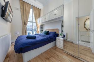 a bedroom with a large bed with blue sheets and a window at Apartment in Baker Street- Huge Balcony in London