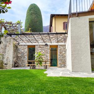 une maison en pierre avec un grand bush derrière elle dans l'établissement Rustico Mulino1 - Fully Renovated Near Locarno and Ascona, à Minusio