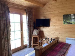 1 dormitorio con 1 cama y TV en la pared en Auchenlea lodges, en Glasgow